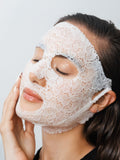 Woman wearing a dermovia lace face mask against a plain background