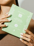 Green skincare product box held by a person with a neutral background
