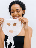 Woman holding a white face mask against a plain background