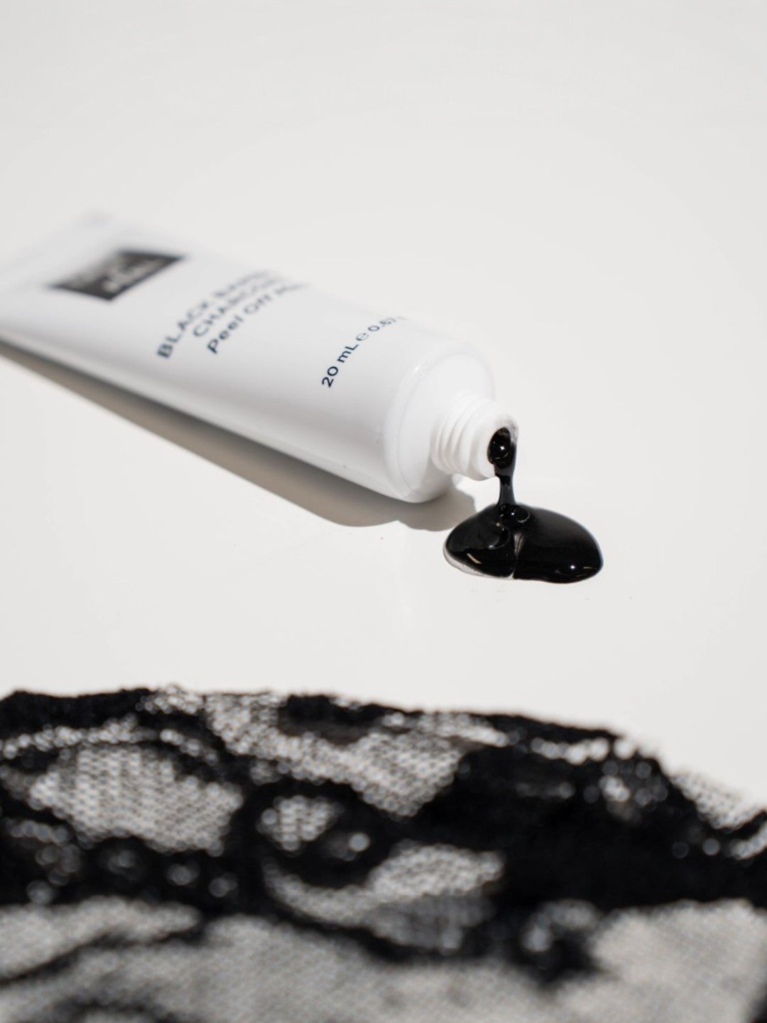 White tube of blackhead removal product with black gel on a white background