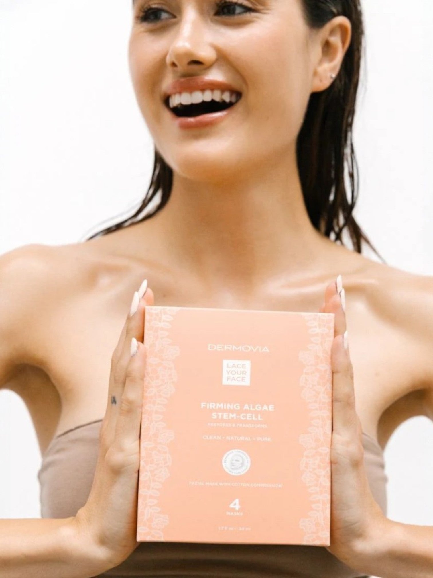 Woman holding a dermovia firming mask box with a plain background
