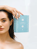 Woman holding a blue skincare product box against a white background